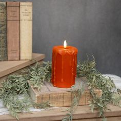 an orange candle sitting on top of a stack of books