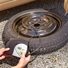 a man is checking the tire pressure on his car's flat tire with an electronic meter