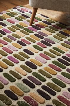 an area rug with multicolored circles on it in front of a chair and footstool