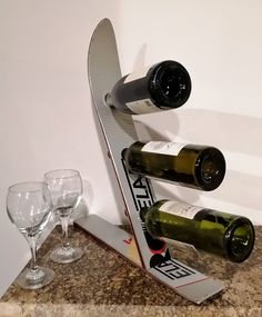 two wine glasses are sitting on a counter next to a snowboard shaped wine bottle holder