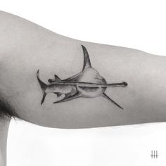 a black and white photo of a man's arm with a shark tattoo on it