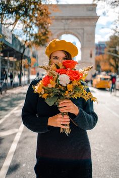 a woman holding flowers in front of the arc de trioe