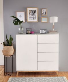 a living room with white furniture and pictures on the wall above it's dresser