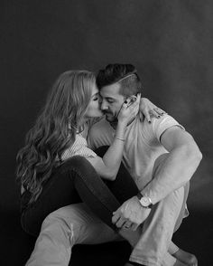 black and white photograph of a man kissing a woman's forehead while she sits on the floor