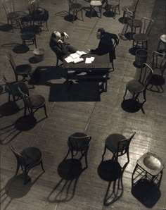 black and white photograph of people sitting at desks in an open area with chairs