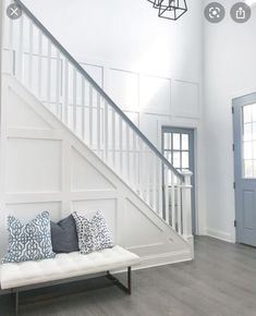 a white couch sitting under a stair case next to a light on a ceiling fan