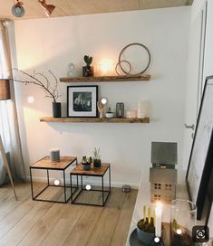 a living room filled with furniture and candles on top of wooden shelves next to a window