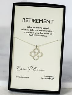 a white necklace with an open heart on it in a black box that says retirement