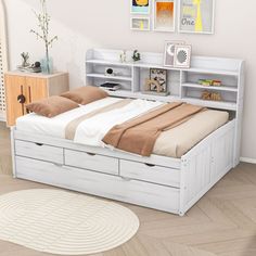 a white bed with drawers underneath it in a room next to a rug and pictures on the wall