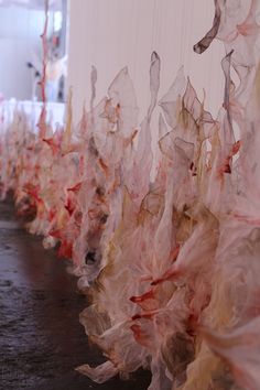 plastic bags are lined up on the floor in front of a wall with red and white ribbons hanging from it