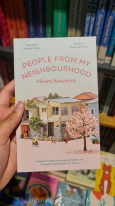 a person holding up a book in front of a bookshelf