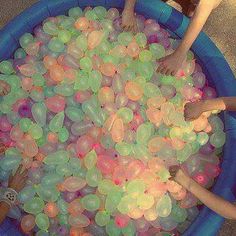 several children are playing in an inflatable pool with water balloons on the floor