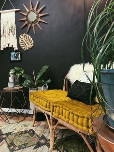 a yellow bench sitting in the middle of a living room next to a potted plant