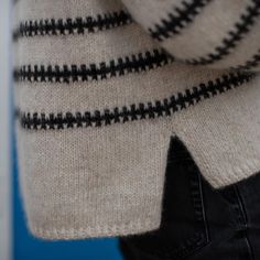 a close up of a person wearing a sweater and black pants with stripes on it