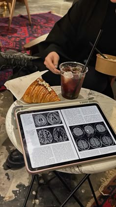 a person sitting at a table with an open book on it and a plate of food in front of them