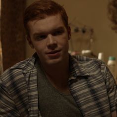 a young man with red hair is looking at the camera while sitting in front of a mirror