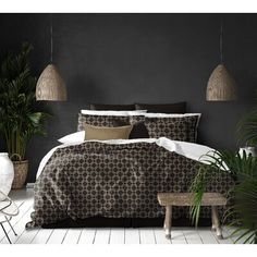 a bedroom with black walls and white flooring is pictured in this image, there are plants on the side of the bed