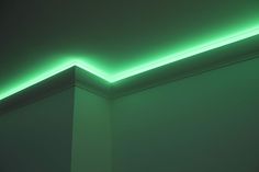 the corner of a room is lit up with green light and there are no lights on it