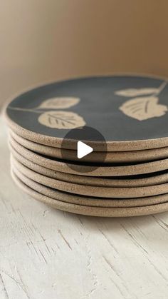 a stack of brown and black plates on top of a wooden table