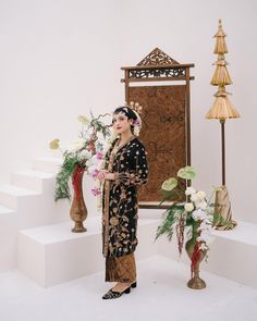 a woman standing in front of a mirror next to flowers