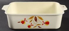 a white casserole with red and yellow flowers painted on the side, sitting on a black surface