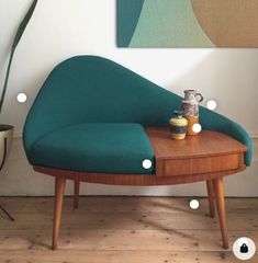 a green couch sitting on top of a wooden table next to a potted plant