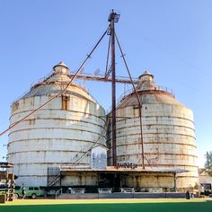 two large silos sitting next to each other on top of a field