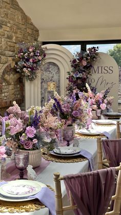 there are many flowers in vases on the tables at this wedding reception table setting