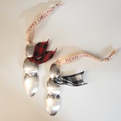 two spoons with ribbons attached to them on a white surface, one is silver and the other is red