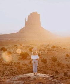 a woman standing on top of a rock in the desert