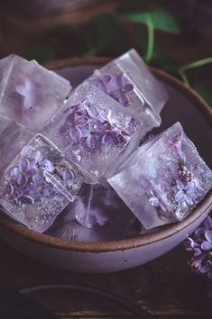 ice cubes with purple flowers in a bowl