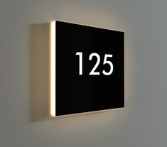 a black and white clock mounted to the side of a wall next to a light