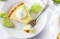 a slice of key lime pie on a white plate with two limes around it