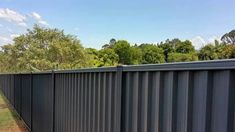 a long black metal fence with trees in the background