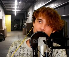 a young man with red hair is holding a microphone in front of his face and looking at the camera