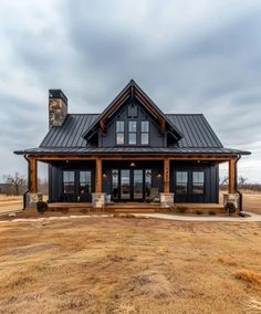 a large black and brown house in the middle of a field