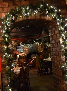 an archway decorated with christmas lights and greenery in a restaurant or bar, during the holiday season