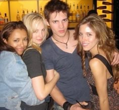 four young people standing together in front of a bar