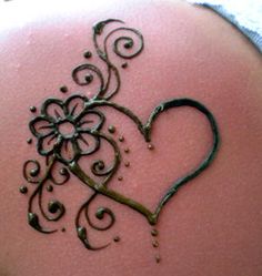 the back of a woman's shoulder with a heart and flower design on it