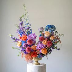 a vase filled with colorful flowers sitting on top of a white tablecloth covered cake