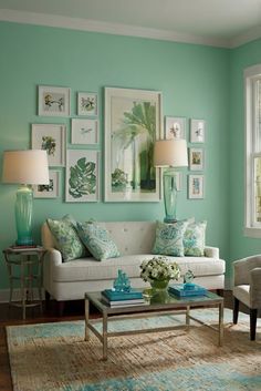 a living room with green walls and pictures on the wall above the couch, coffee table