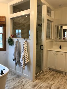 a bathroom with a walk in shower next to a bathtub and sink under a window