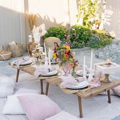 a table set up with pink and white plates, napkins and flowers on it