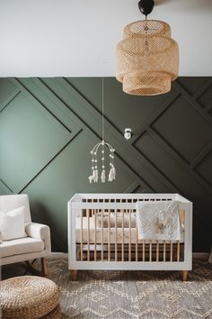 a white crib in a room with green wallpaper and wicker chandelier