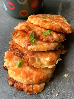 four fried food items stacked on top of each other next to a cup with sauce