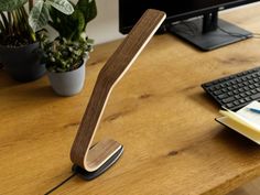 a wooden desk lamp sitting on top of a table next to a keyboard and monitor