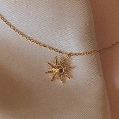 a gold necklace with a sun charm hanging from it