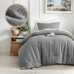 a bed in a bedroom with grey comforter and pillows