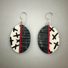 pair of earrings with black and white designs on red striping, hanging from silver earwires