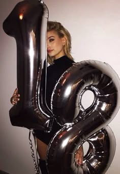 a woman holding an oversized number balloon in her hands